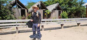 Man standing in a village carrying monitoring equipment